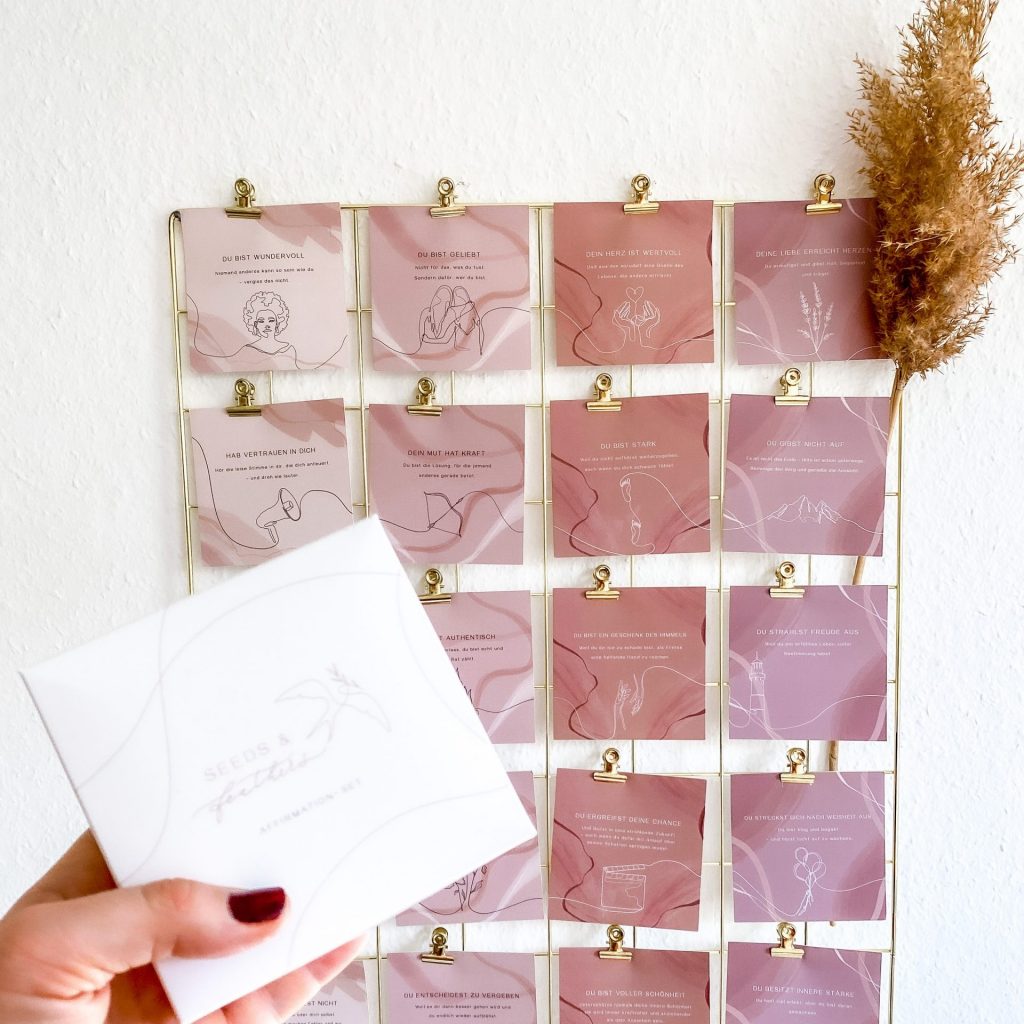 Hand hält eine Karte vor einem Adventskalender aus 24 aufgehängten Karten