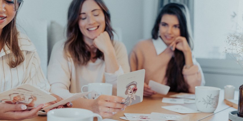 Drei Freundinnen an einem Tisch mit Karten und Tassen