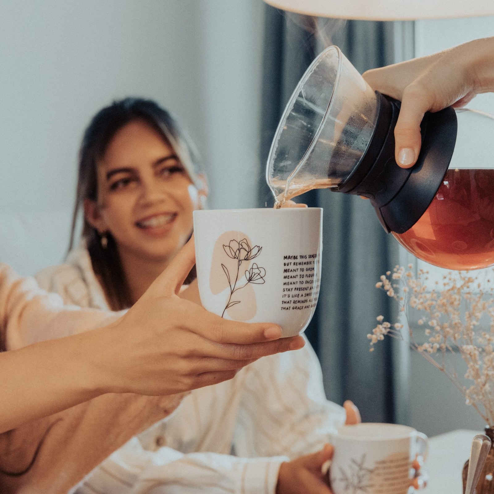 Eine Frau reicht einer anderen eine Tasse mit Spruch